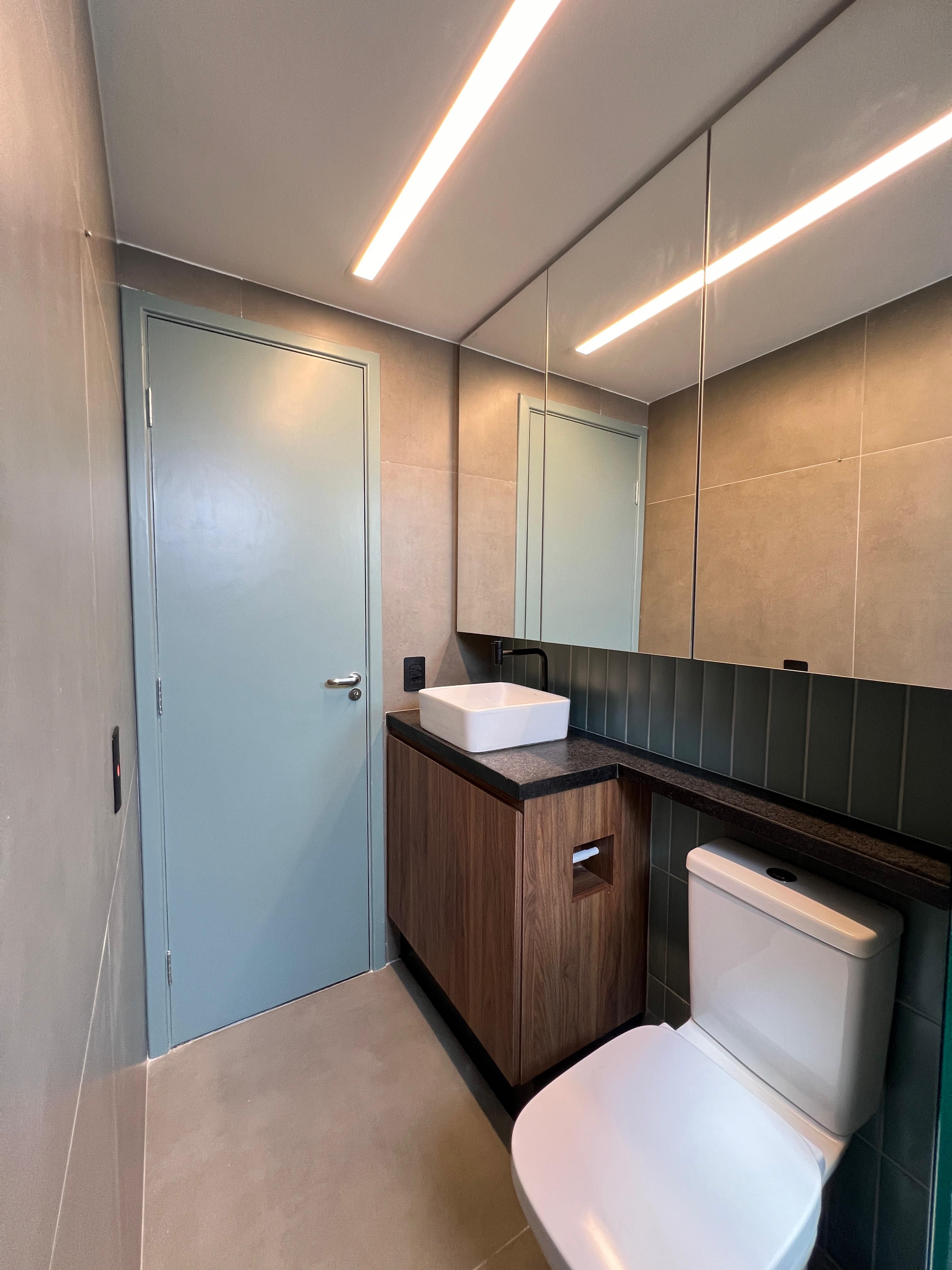 Banheiro moderno com pia dupla, espelho grande e iluminação embutida, criando um ambiente elegante e funcional.