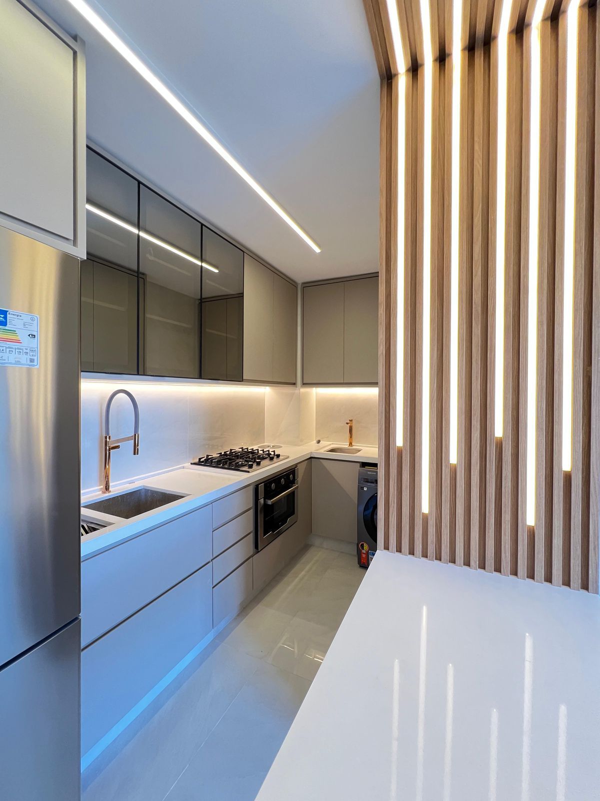 Cozinha planejada com armários superiores com portas de vidro, iluminação interna e um design que une o clássico e o moderno.