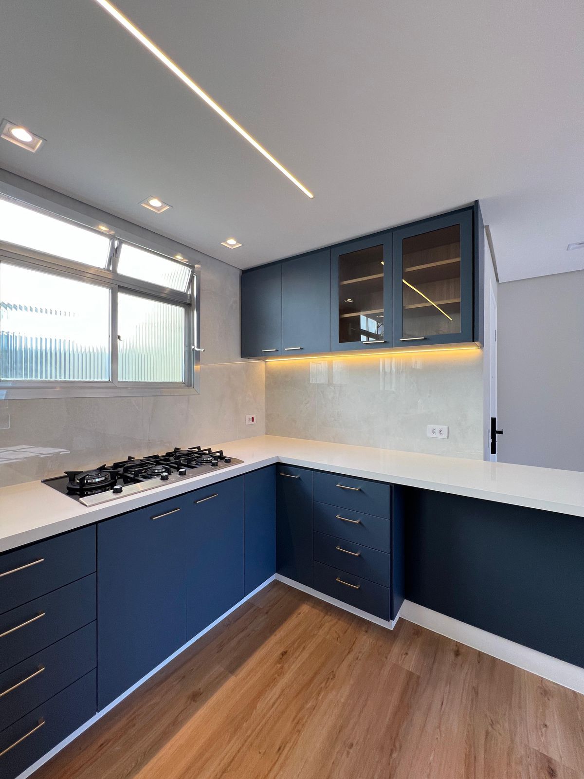 Cozinha com península, armários em tom fendi e bancada de silestone, ideal para cozinhar e socializar.