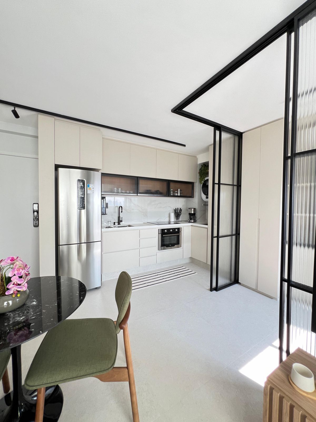 Cozinha planejada com armários brancos, bancada de madeira e eletrodomésticos modernos.