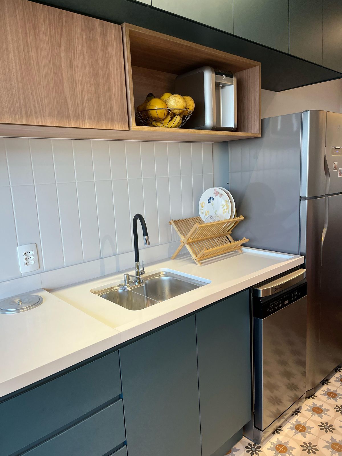 Cozinha planejada com armários em madeira clara, bancada de granito e iluminação moderna, proporcionando um ambiente acolhedor e prático.