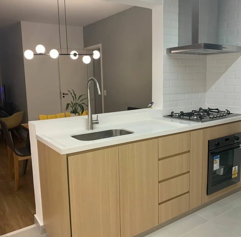 Cozinha planejada com armários de madeira escura, ilha central e iluminação embutida.