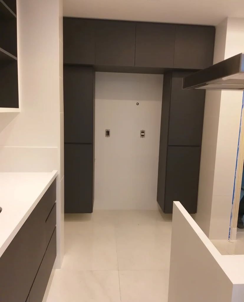 Cozinha com design arrojado, armários em acabamento metálico e iluminação cênica que destaca os detalhes do projeto.