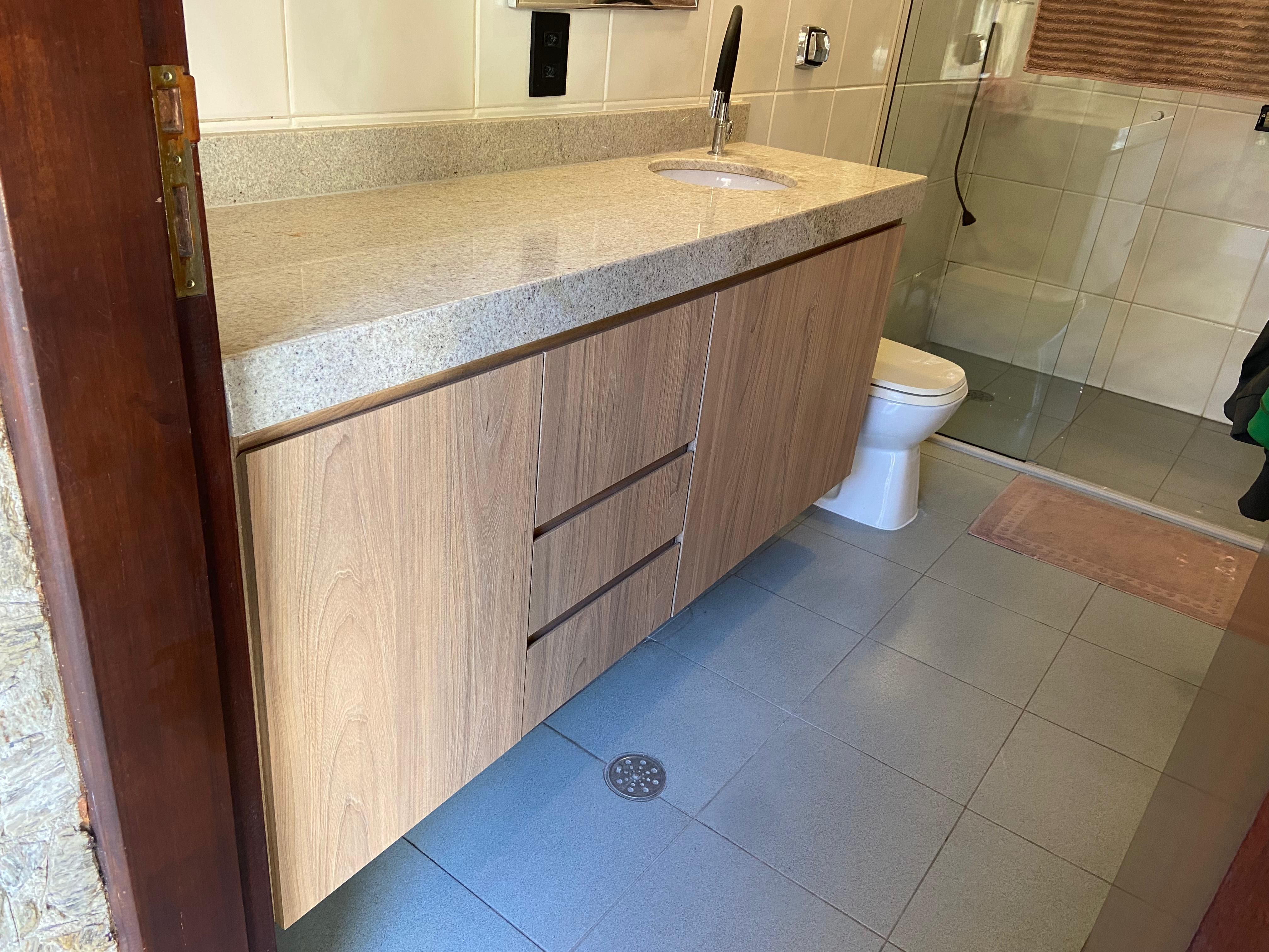 Banheiro espaçoso com duas pias, armários embutidos e iluminação natural, oferecendo praticidade e conforto.