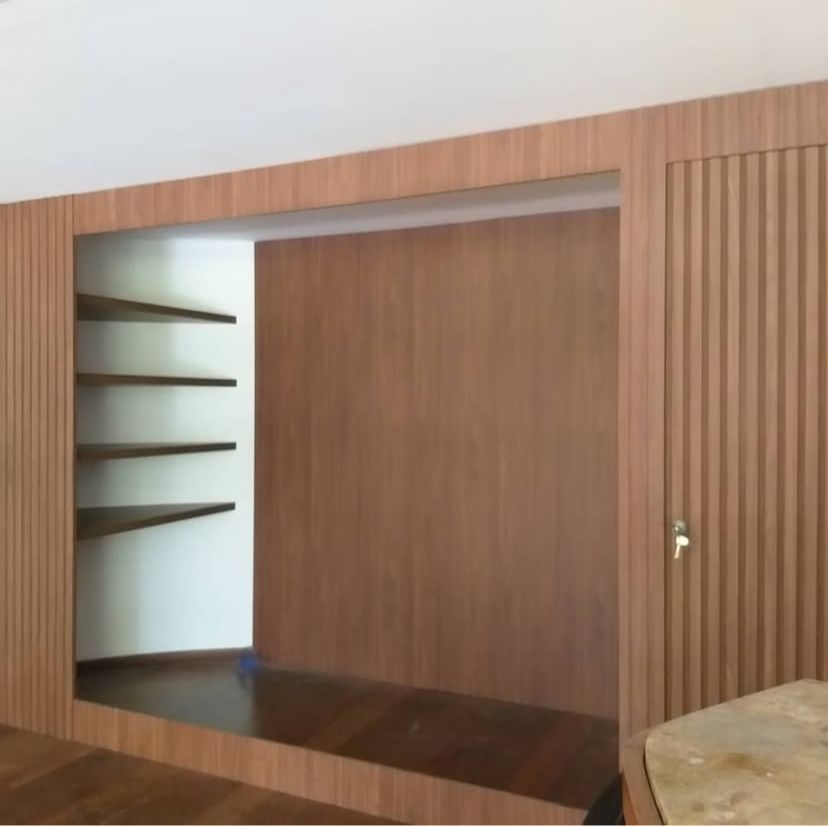 Sala de estar elegante com sofá azul, mesa de centro de vidro e iluminação moderna, oferecendo um espaço estiloso e confortável.