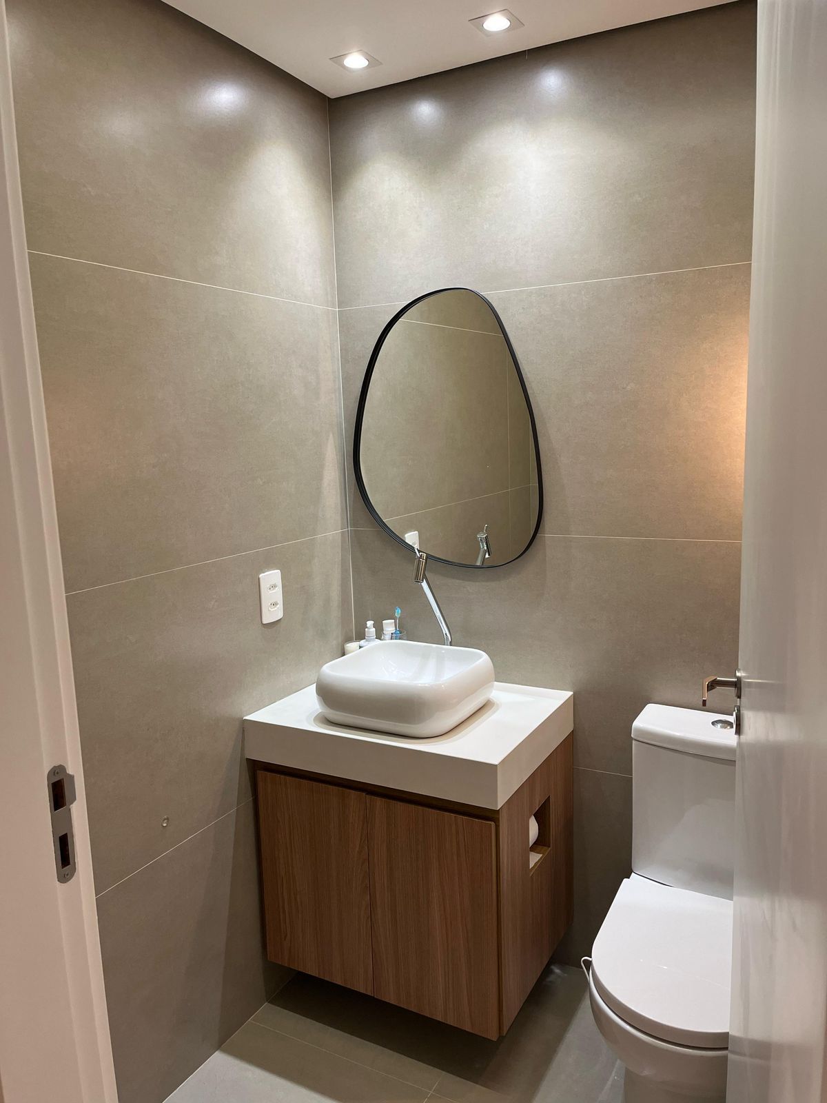 Banheiro com design rústico, apresentando revestimentos em pedra, bancada de madeira e elementos naturais, criando um ambiente acolhedor.