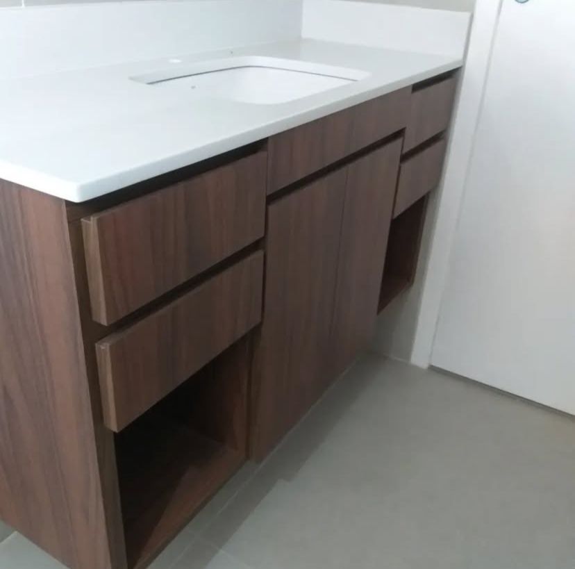 Banheiro moderno com chuveiro de teto, pia de concreto e iluminação embutida, oferecendo um espaço funcional e estiloso.