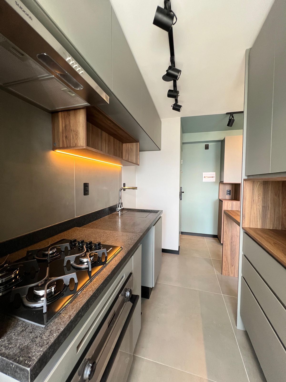 Cozinha com armários em laca azul, bancada de madeira e ladrilho hidráulico, trazendo cor e personalidade ao ambiente.